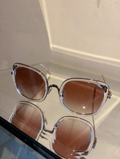 Occhiali da sole Coach lenti rosa con disegno strass laterali.