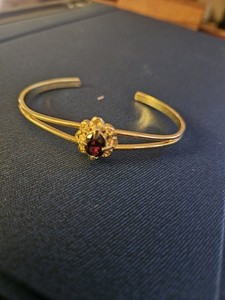 Authentic vintage gold-plated bangle bracelet features a genuine garnet focal stone set...