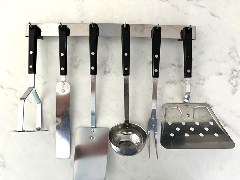 A complete matched EKCO Forge stainless set with its original hanging rack — a rare, display-ready MCM kitchen trophy that's actually still usable.