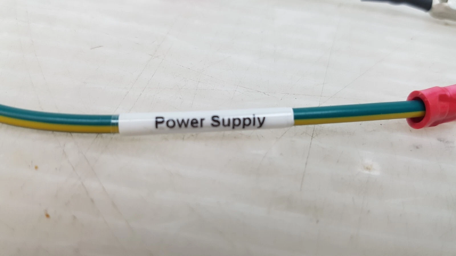 Green/yellow ground wire with sleeve label reading Power Suppiy and red ring terminal