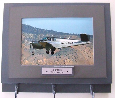 Wall Mounted Keychain Rack with a 4''X6'' print of a Beechcraft Bonanza aircraft.