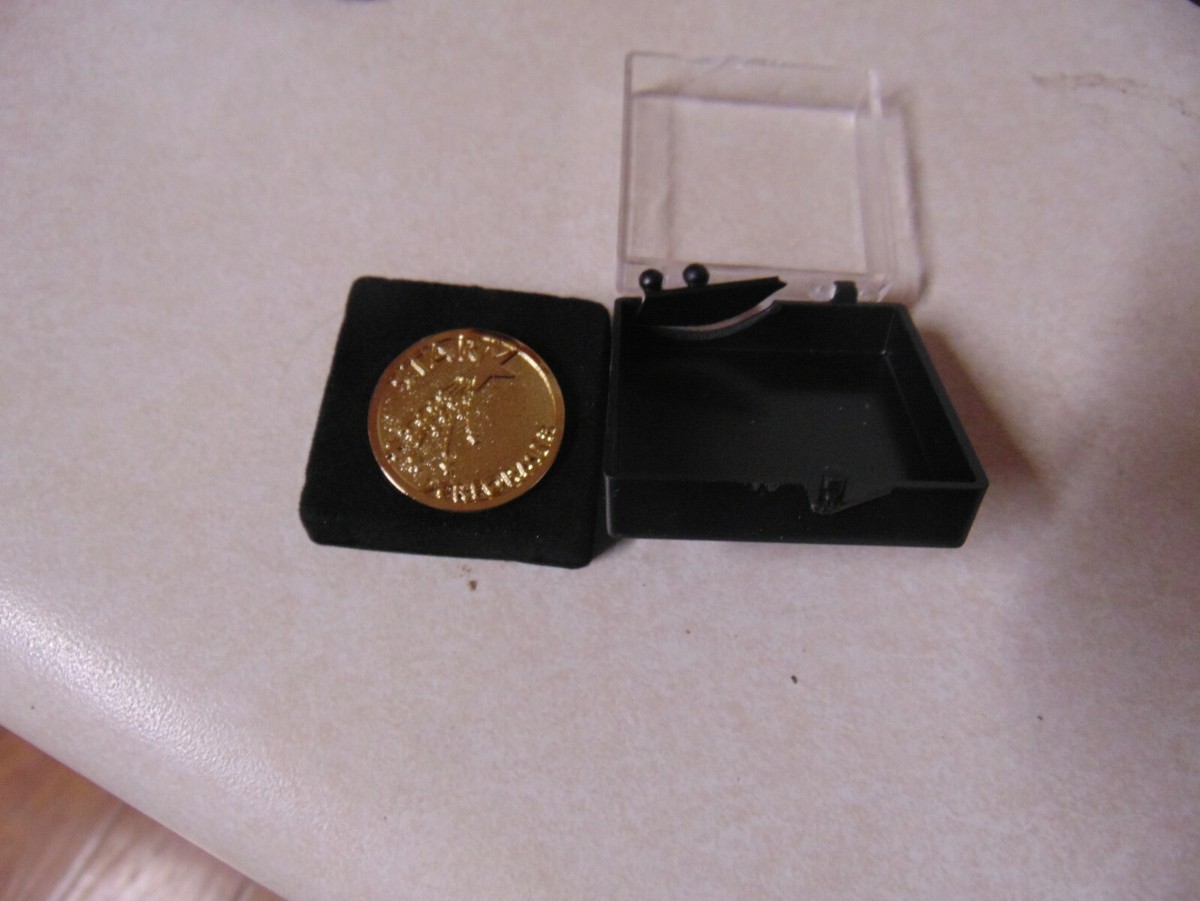 GOLD COLORED DISK WITH 1 CLUTCHBACK IN DISPLAY CASE ABOUT 1 INCH