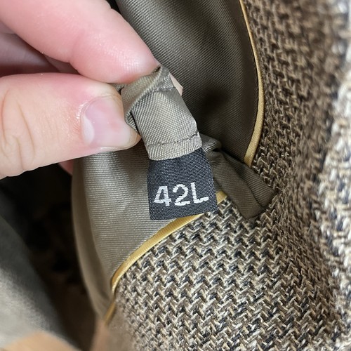 Close-up of Haggar men's sport coat with black size 42L tag, two-button front, and beige textured plaid fabric.