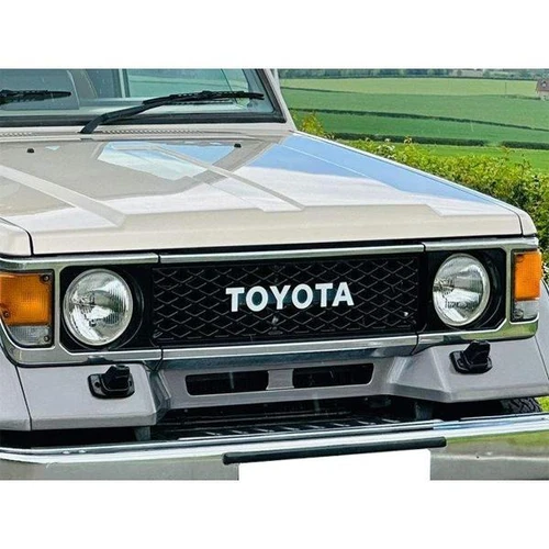 Black Toyota LandCruiser 75 front grille with dual round headlights and white “TOYOTA” text on the lower center.