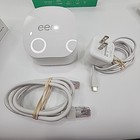 White Eero 6+Plus dual band mesh WiFi router with black top and visible rear Ethernet port, shown with attached white power adapter and cable.