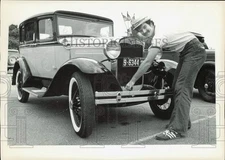 1977 Press Photo Man salutes as he shows off antique car - lrb43147