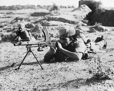An Indian sepoy lying on his stomach to operate a machine gun duri- Old Photo