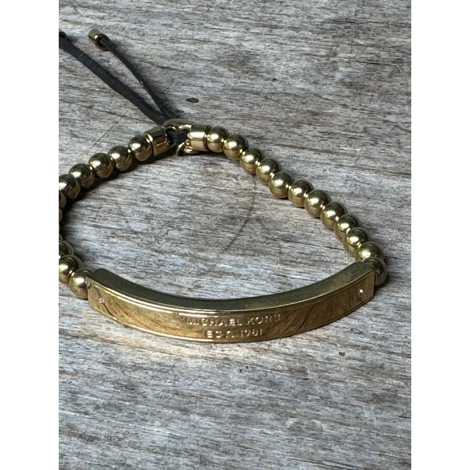 Pulsera Michael Kors tono dorado con cuentas con barra grabada y cordón ajustable Foto 2 de 4