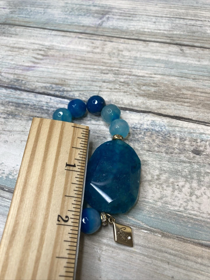 Pulsera elástica ágata azul de lentejuelas de diseñador. Diamantes de imitación con logotipo en tono dorado Foto 3 de 4