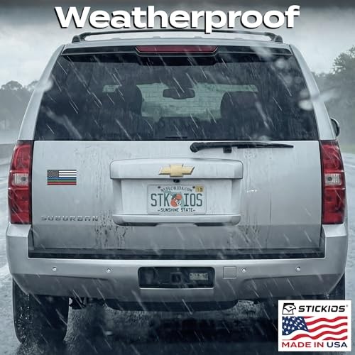 Silver Chevrolet Suburban with American flag sticker, rain-soaked rear window, and “STK IO” plates.