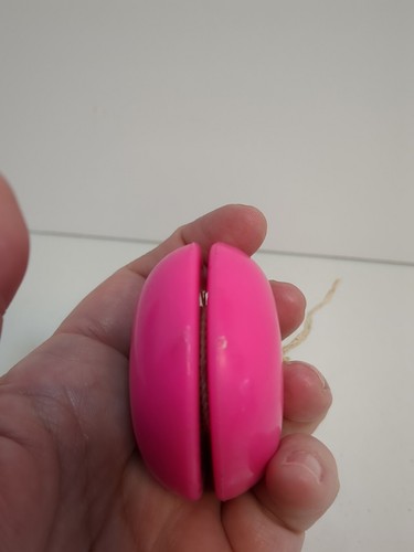 Hand holding a 1994 Duncan Neo Yo-Yo in hot pink neon green with yellow string, made in USA.