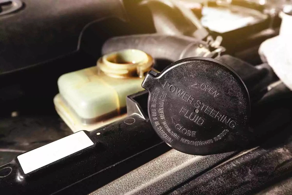 An open power steering fluid reservoir. The cap is resting on the edge of the engine compartment.