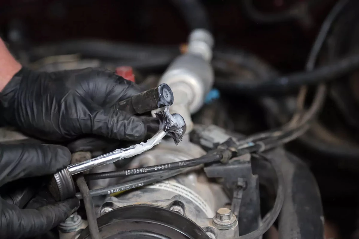 A mechanic coats the inside of two spark plug boots with dielectric grease.
