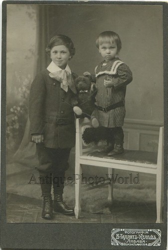 Two cute Russian children with teddy bear toy antique cabinet photo