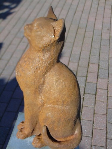 chat assis en fonte pat rouillé .