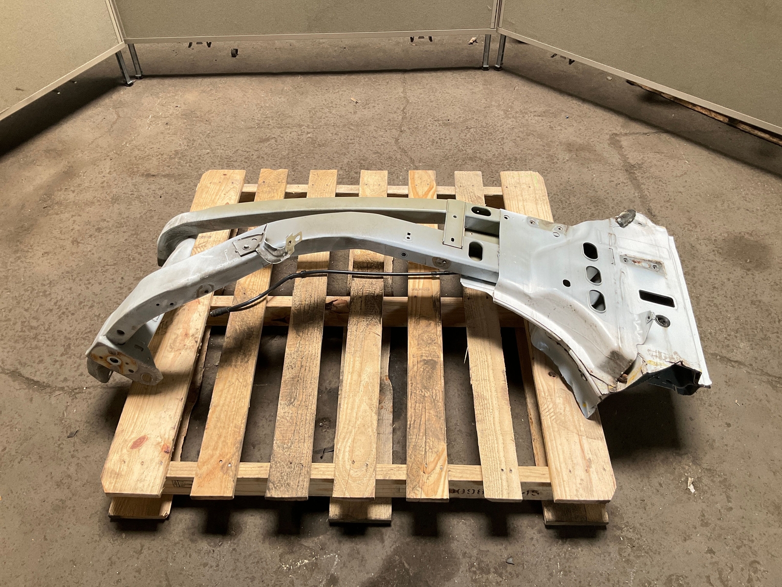 Silver 13-18 RAM 1500 front left driver frame apron radiator support on worn concrete, resting on a wooden pallet.