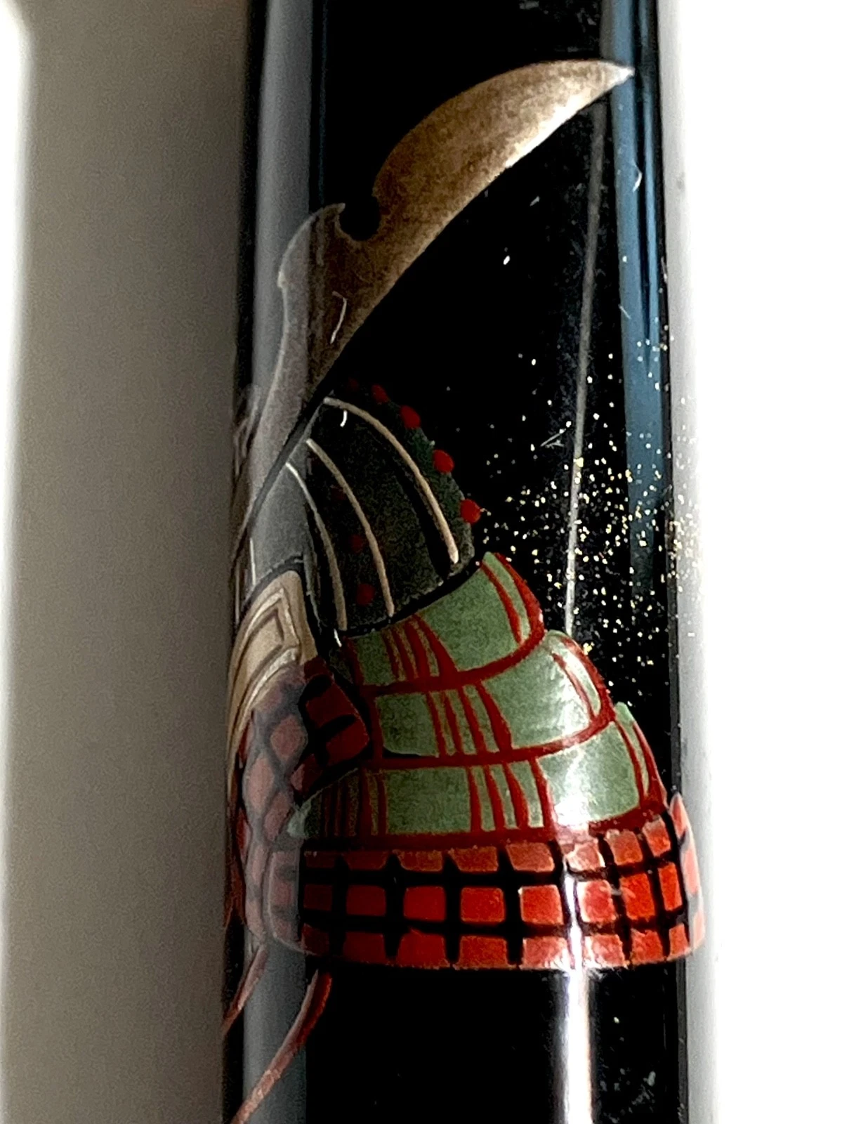Black vintage fountain pen with gold accents, featuring detailed red, green, and silver armor design on the side.