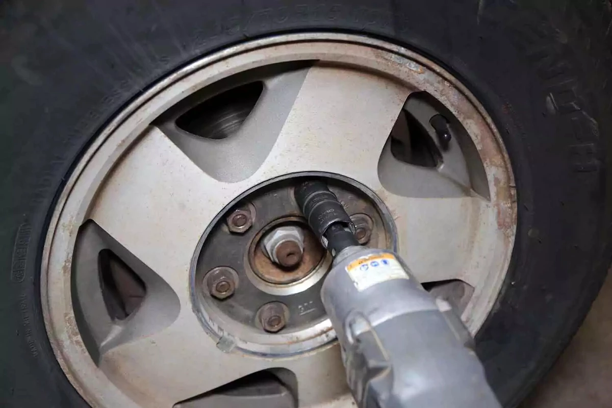 A mechanic removes a lug nut with an impact gun.
