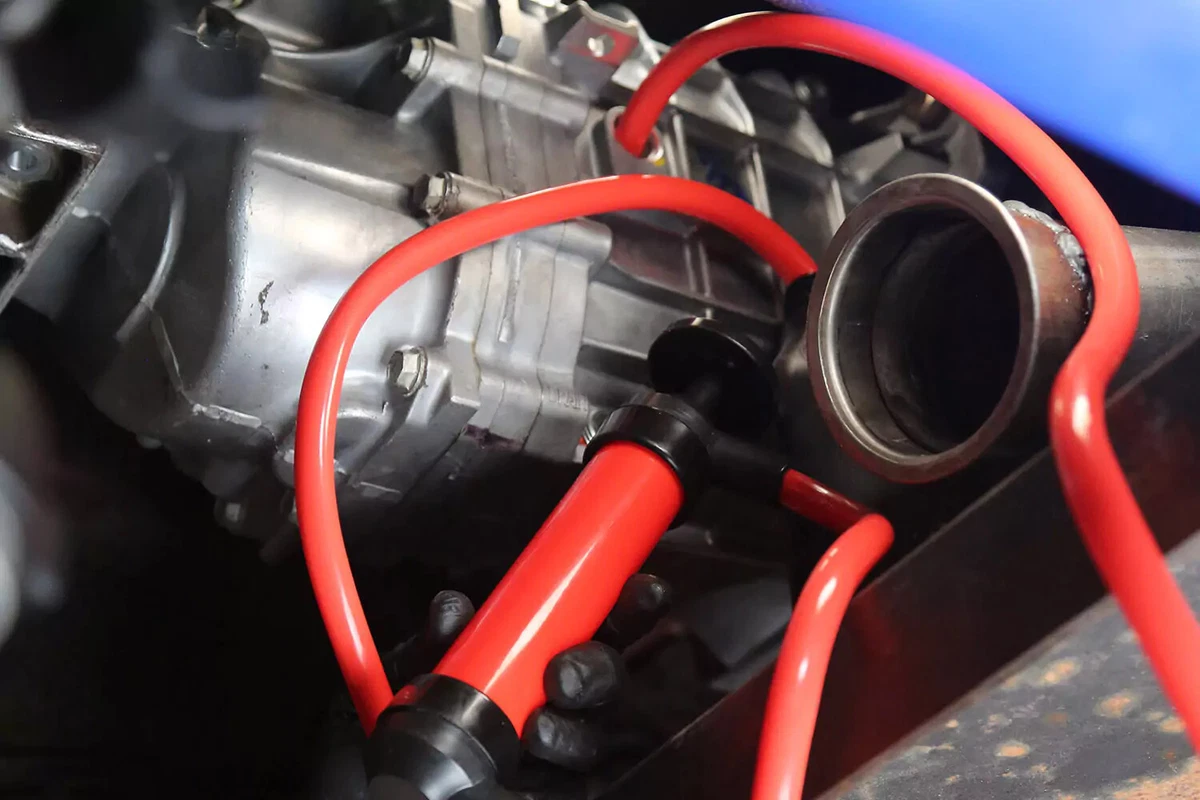A pump with one orange hose inside the open fill port of a manual transmission.