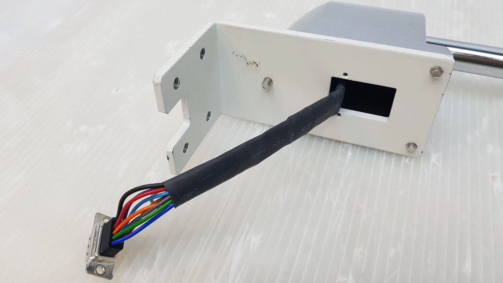 White steel L-bracket with cable exit and D-sub connector