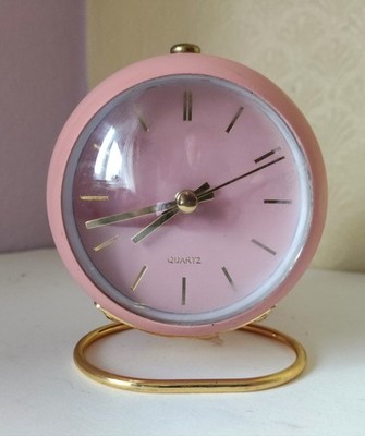 Nordic Design runder rosa Wecker auf goldfarbenem Ständer.