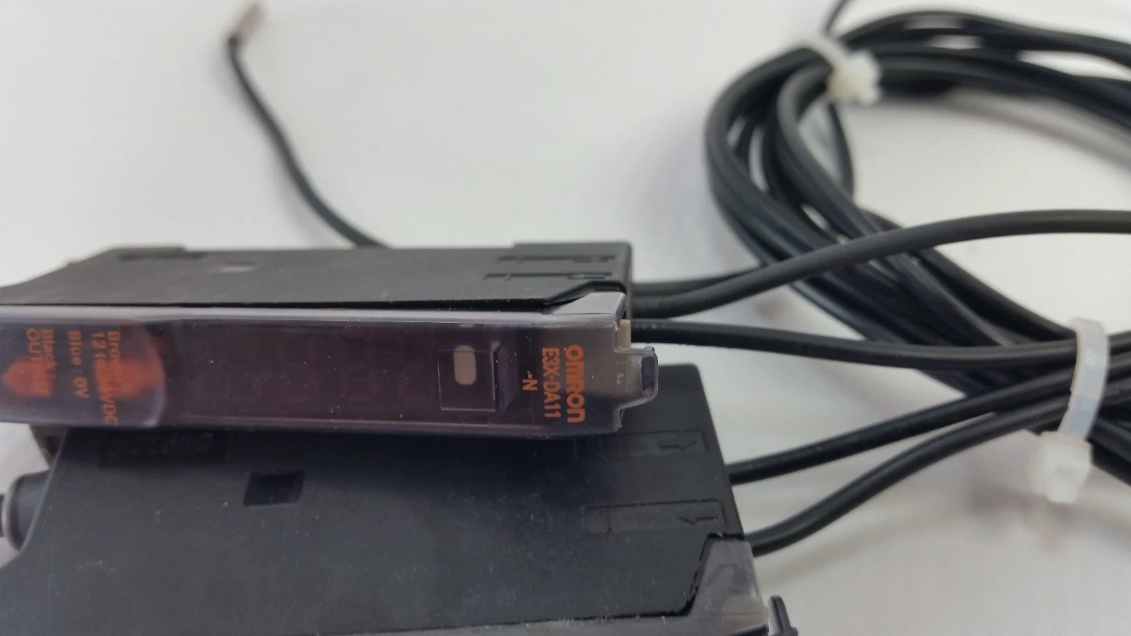 Omron E3X-DA11-N amplifier front with fiber cables routed through a cable tie