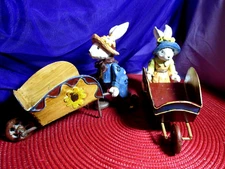 Pair of Metal Folk Art Primitive Bunny Rabbits Dressed Up Pushing Cart Figurines