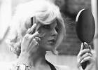 Portrait of actress Joan Collins brushing a blonde wig on her head- Old Photo