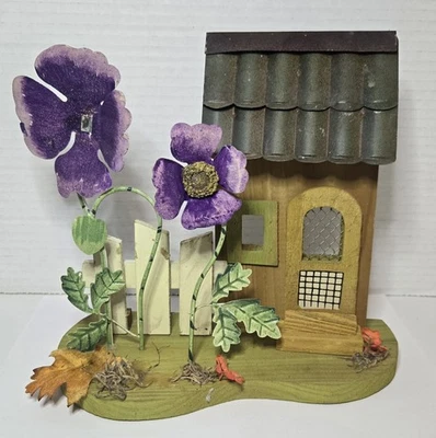 Casa de hadas decorativa de madera con flores de metal púrpura y una pequeña cerca Foto 1 de 4