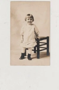 Cartolina foto reale RPPC AZO 1904-1918 bambino piccolo in posa accanto alla sedia spedizione gratuita - Foto 1 di 2
