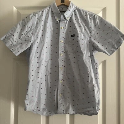 Camisa RVCA Manga Corta Abotonada Talla L Niños Ajuste Con Bolsillo Azul Claro Con Diseño Rojo Foto 1 de 4