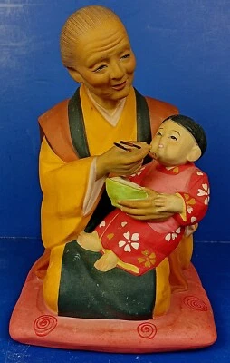 VINTAGE JAPANESE CLAY HAKATA URASAKI DOLL ‘GRANDMOTHER FEEDING GRANDCHILD' - Image 1 of 4
