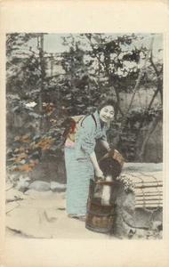 Postal coloreada a mano mujer japonesa sonriente vierte agua lavado arroz - Imagen 1 de 2