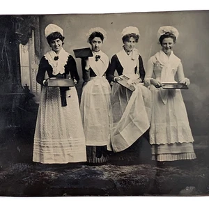 Foto a colori professionale donne che indossano uniformi da cameriera che tengono vassoi da servizio - Foto 1 di 5
