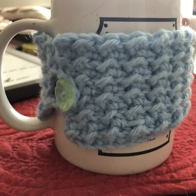 Acogedora taza de ganchillo acrílico azul claro con botón verde para bebidas cálidas Foto 1 de 2