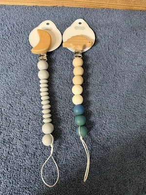 X 2 Nuevo Clip Chupete Silicona Mudpie Madera Dino Y Luna Pacy Crema y Azul Foto 1 de 4