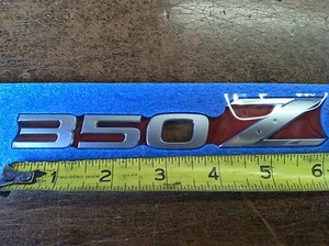 NEW OEM NISSAN 2003-2008 350Z FACTORY REAR DECK / HATCH / TRUNK EMBLEM - Picture 1 of 2