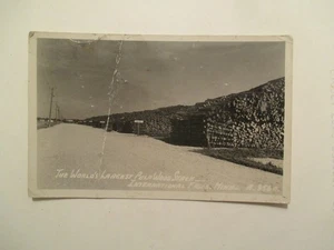 Tarjeta postal RPPC International Falls Minnesota pulpa madera pila foto real MN - Imagen 1 de 2