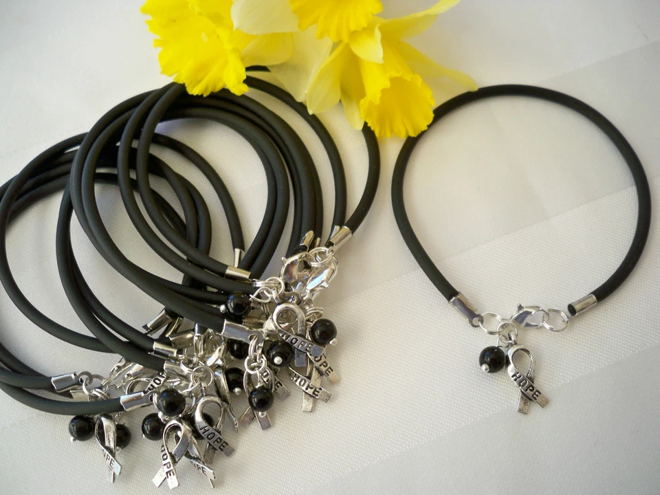 PULSERAS CONCIENCIACIÓN CÁNCER PIEL MELANOMA 1 DZ/DIJE CINTA NEGRO/ESPERANZA' Foto 1 de 1