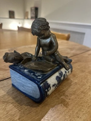 Coffret à bijoux en porcelaine et bronze. Un ange chérubin assis sur un livre. - Photo 1/4