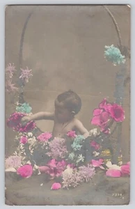 Foto postal RPPC bebé en cesta llena de flores coloreada a mano vintage - Imagen 1 de 2