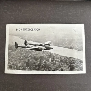Military AIRPLANE Postcard P-38 Interceptor in flight over metropolis RPPC #2862 - Foto 1 di 2
