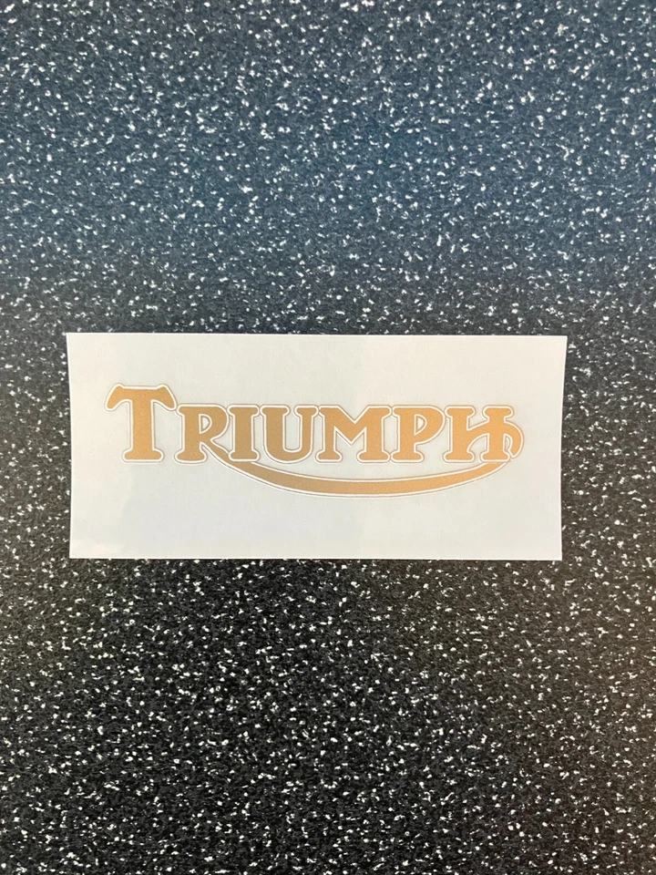 Triumph - 2 off vinyl self adhesive sticker 70x35mm (Gold on clear) - Image 1 of 1