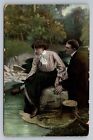 Romantyczna para siedząca nad rzeką kobieta zdejmująca but stara pocztówka lata 1900.
