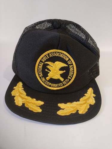 Black trucker hat with yellow National Rifle Association logo and text, featuring two yellow leaf emblems on the front panel.