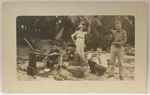 Postal con foto real RPPC~HOMBRE ABRIENDO UN COCO EN PICNIC EN PLAYA - Imagen 1 de 3