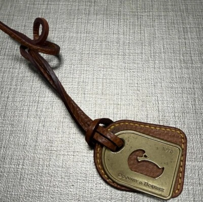 Etiqueta colgante de cuero marrón y latón con logotipo de pato Dooney & Bourke para bolsos Foto 1 de 4