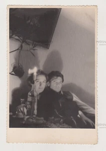 Couple Sits in Room Illuminated by Candle Stuck in Bottle of Spirits Abstract - Picture 1 of 7