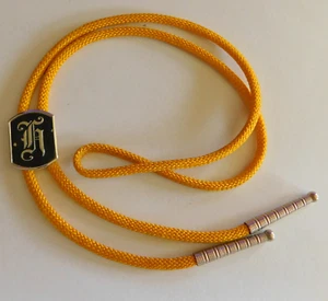 VINTAGE BOLO TIE "SWANK" STYLIZED INITIAL "H" MEDALLION YELLOW CLOTH STRING TIE - Picture 1 of 4