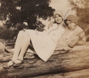 1930s Two Girls Sitting Log Playful Outfits Smiling Natural Setting Portrait - Picture 1 of 3